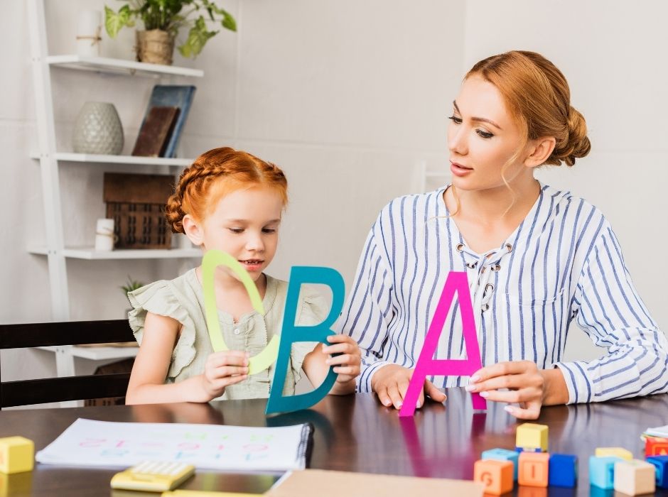 children read. teacher or mother that teaches alphabet to a girl