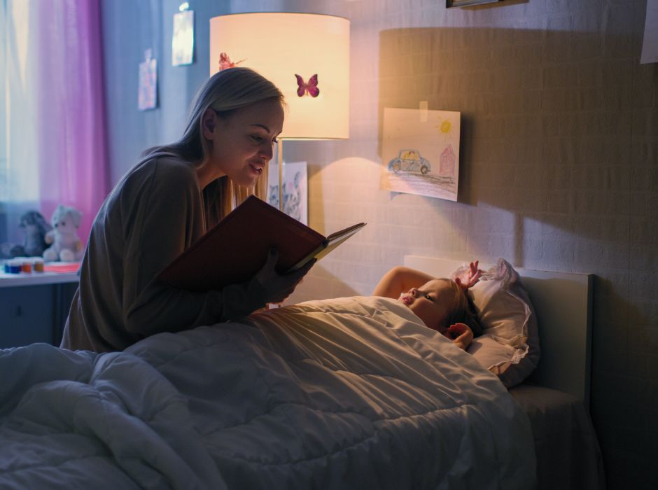 return to school, mother reading a book to her child in the bed